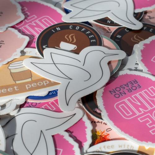 Minimalist bird sticker featuring the Poetry Rise dove logo surrounded by other vinyl stickers for water bottles